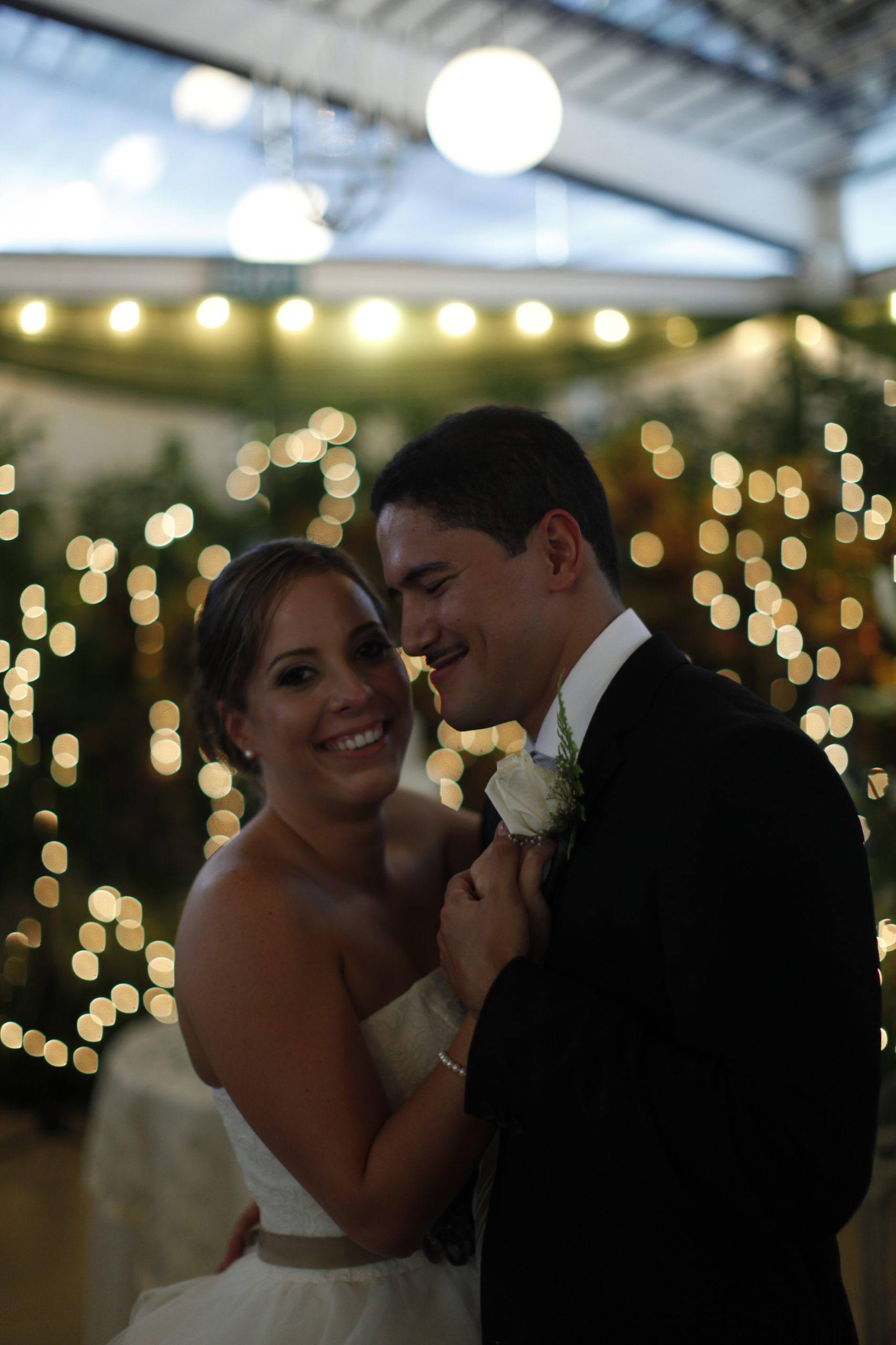 Bride and groom dancing in front of fairy lights